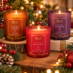 Personalized Christmas scented candles in amber, red, and purple glass jars, displayed with festive greenery, pinecones, and warm holiday lights.