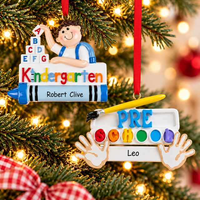 Personalized first day of school Christmas ornaments featuring a kindergarten student with alphabet blocks and a colorful preschool ornament with paintbrush and handprints, hanging on a Christmas tree.