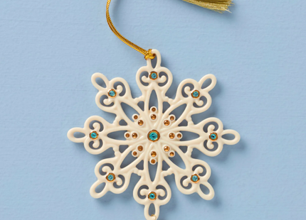 Decorative snowflake ornament with gemstones and a tassel on a blue background