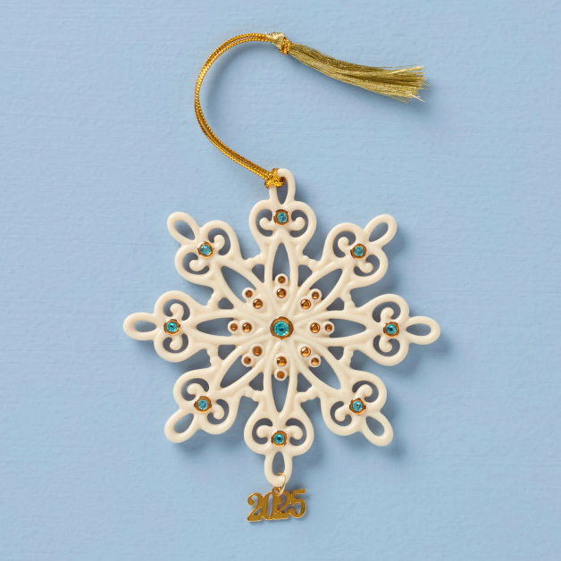Decorative snowflake ornament with gemstones and a tassel on a blue background