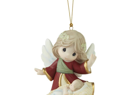 Precious Moments Christmas ornament featuring an angel with white wings watching over a sleeping baby in a manger-style bed.