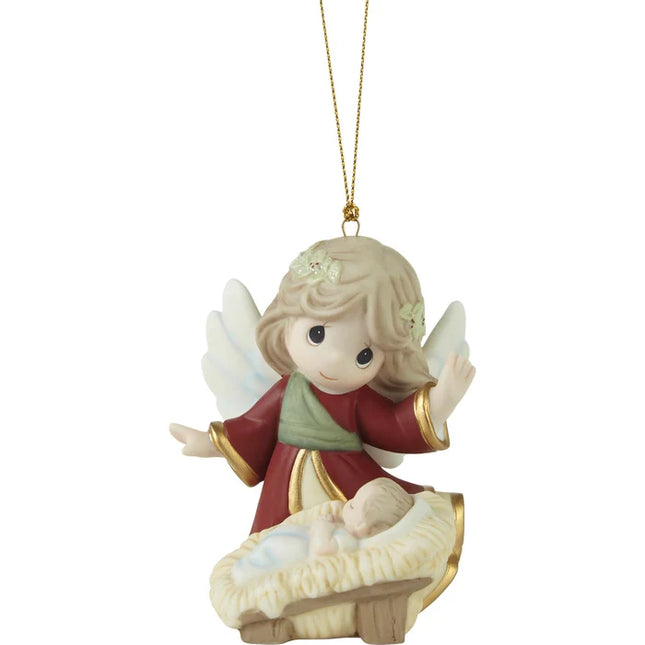 Precious Moments Christmas ornament featuring an angel with white wings watching over a sleeping baby in a manger-style bed.