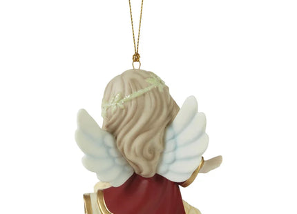 Precious Moments Christmas ornament featuring an angel with white wings watching over a sleeping baby in a manger-style bed.