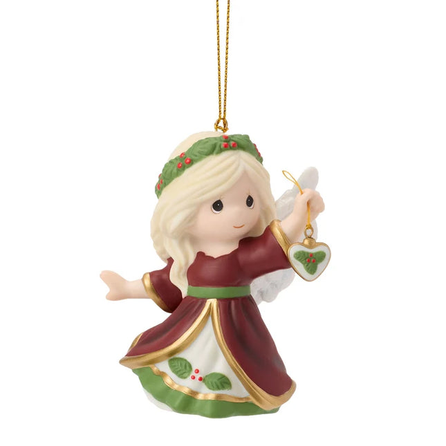 Precious Moments Christmas angel ornament featuring a blonde angel in burgundy and green holding a small heart ornament decorated with holly.