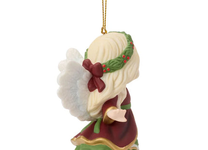 Precious Moments Christmas angel ornament featuring a blonde angel in burgundy and green holding a small heart ornament decorated with holly.