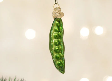 Old World Christmas green peas in a pod glass ornament with dimensional peas and sparkling accents hanging from a Christmas tree.
