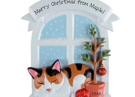 Personalized calico cat Christmas ornament by a snowy window with custom name and year.