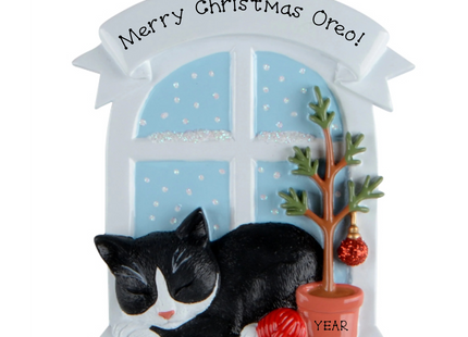 Personalized tuxedo cat Christmas ornament by a snowy window with custom name and year.