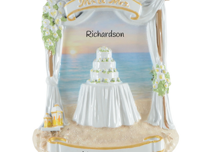 Personalized beach wedding Christmas ornament with ocean backdrop, wedding cake, custom couple name and wedding date.
