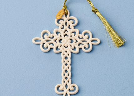 Decorative cross ornament with intricate patterns and a gold tassel on a light blue background