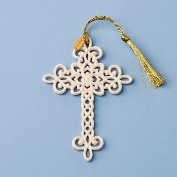 Decorative cross ornament with intricate patterns and a gold tassel on a light blue background