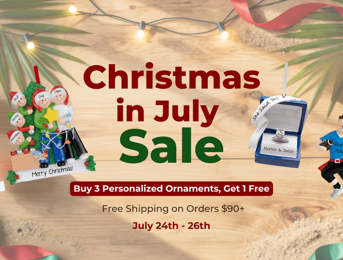 Promotional sale graphic for Christmas personalized ornaments, featuring several small ornament examples on a sandy holiday-themed background with palm leaves, string lights, ribbons, and large text reading 'Christmas in July Sale' plus offer details.