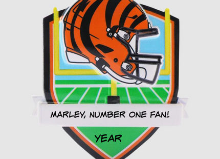 Personalized Cincinnati Bengals football helmet Christmas ornament with custom name and year on a football field background.