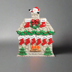 Decorative Christmas house ornament with stockings, wreath, and Santa Claus on a white background