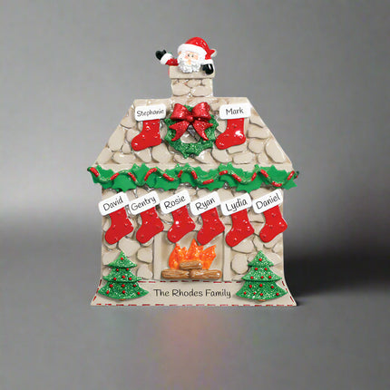 Decorative Christmas house ornament with stockings, wreath, and Santa Claus on a white background