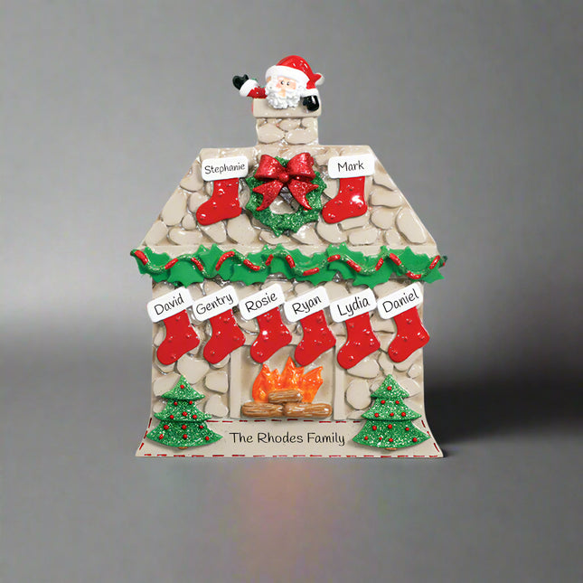 Decorative Christmas house ornament with stockings, wreath, and Santa Claus on a white background