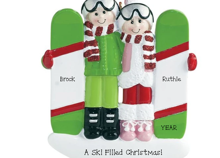 Personalized skiing couple Christmas ornament featuring two skiers in winter outfits with green skis, custom names, holiday message, and year.