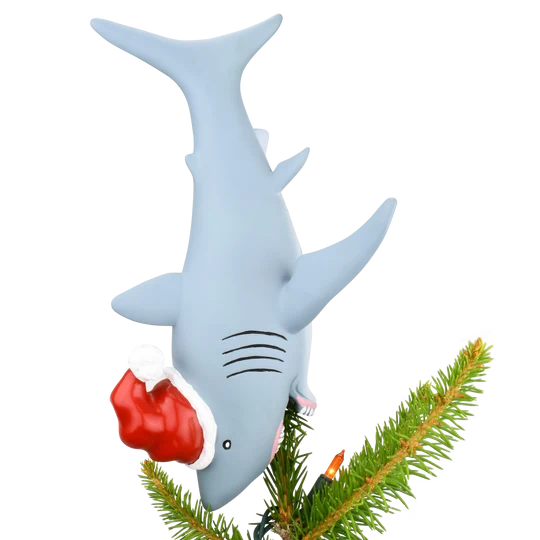 Gray shark Christmas tree topper diving headfirst into a Christmas tree while wearing a red and white Santa hat.